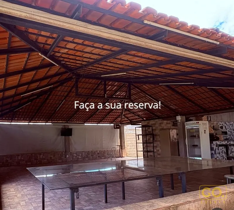 Área coberta com telhado de telha cerâmica, mesas de vidro e balcão de bar ao fundo, sem pessoas presentes.