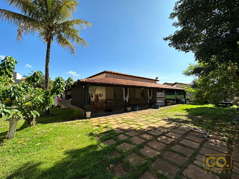 Casa térrea de estilo campestre com varanda coberta, telhado de telha cerâmica e gramado amplo sob céu azul com palmeira.